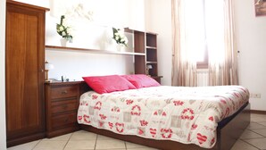 A bedroom with a bed, a nightstand, a dresser, and a window with curtains. - Art Apartment Bandinelli (Florence)