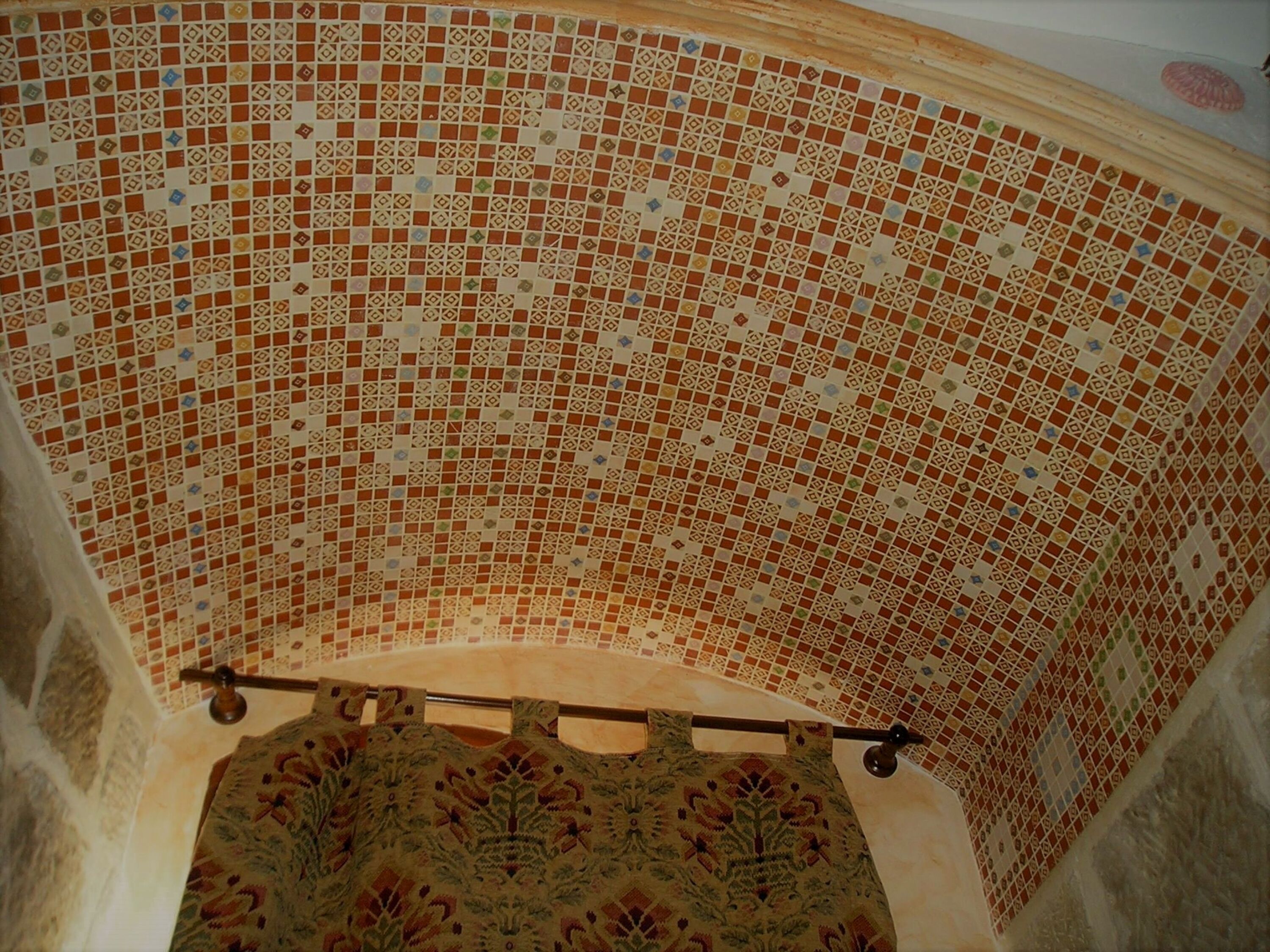 Una stanza con soffitto piastrellato e tappeto decorato sul pavimento.