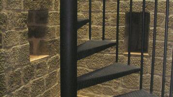 A spiral staircase with metal railings against a stone wall.