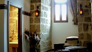 A stone-walled room with a small window, a door, and two wall-mounted lights. - TORRE FUERTE S.XIII (Baños de Rioja)