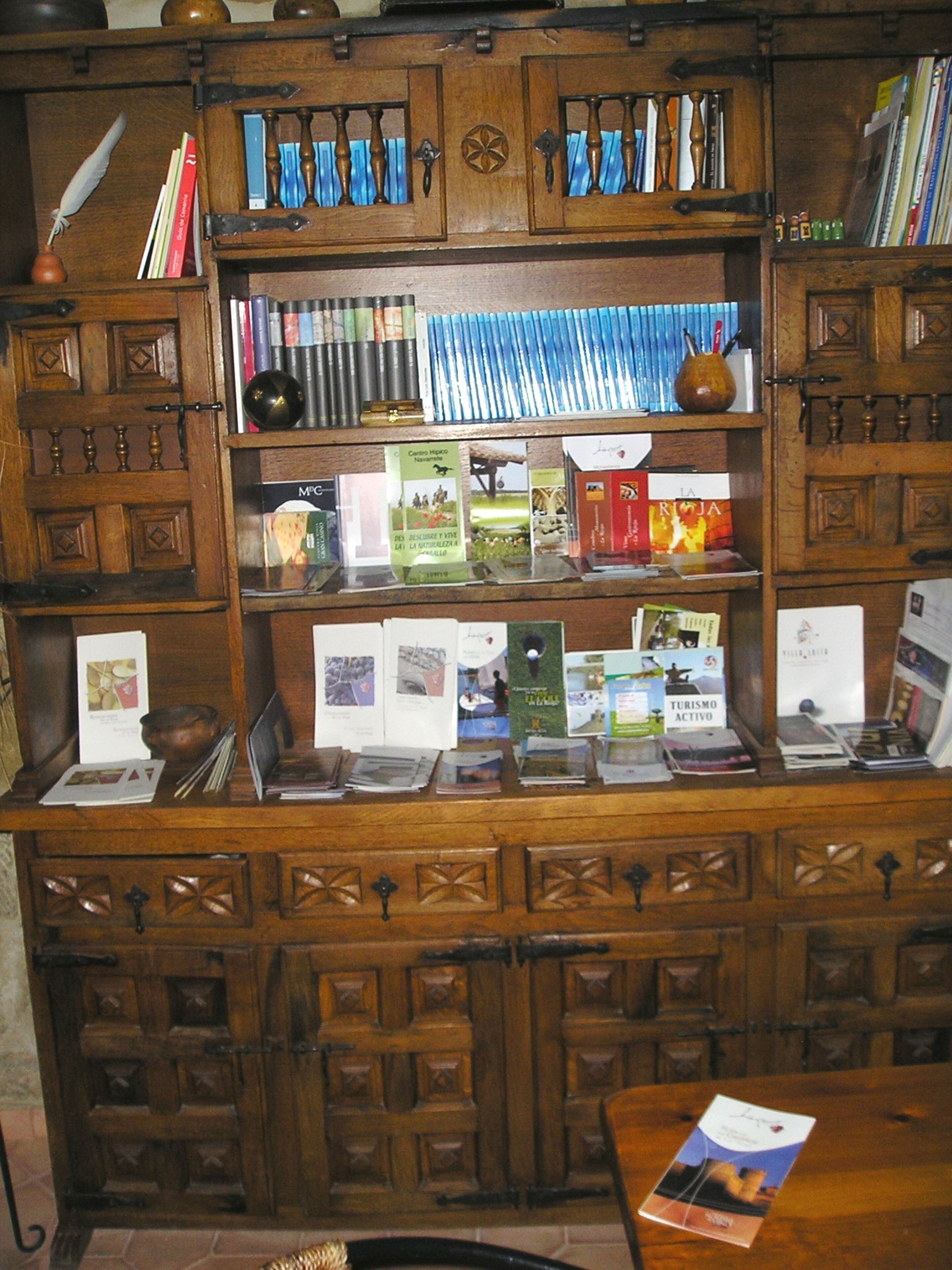 A wooden bookshelf with books and pamphlets, a feather quill, and a small globe.