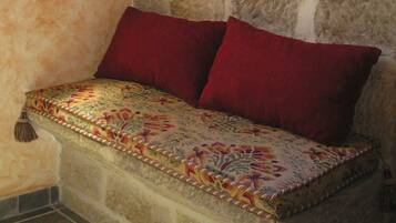 A stone wall with a patterned bench and red cushions.