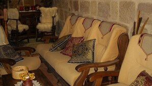 A stone-walled room with a wooden sofa, chairs, and a table with a vase and papers. - TORRE FUERTE S.XIII (Baños de Rioja)