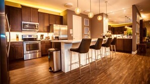 A modern kitchen with stainless steel appliances, a central island with bar stools, and pendant lighting. - Aco259112 - The Encore Club Resort - 8 Bed 8 Baths Villa (Kissimmee)