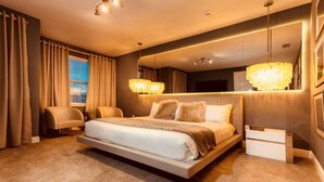A modern bedroom with a large bed, a bedside table, a chair, and a large mirror. - Aco259112 - The Encore Club Resort - 8 Bed 8 Baths Villa (Kissimmee)
