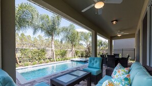 Un espace extérieur abrité, doté d’une piscine, de meubles en osier et offrant une vue sur les arbres et une clôture.
