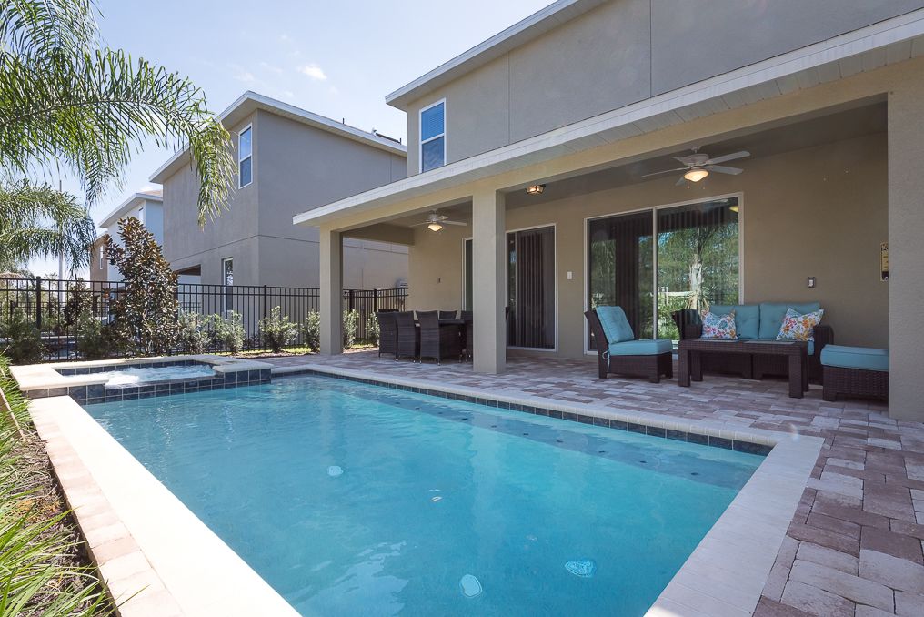 A swimming pool with a patio area, outdoor furniture, and a covered seating area.