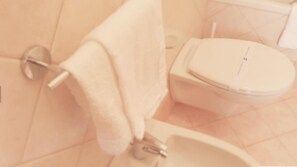 A bathroom with a toilet, a sink, and a towel hanging on a rack. - Green Park Residence (Bagnara Calabra)