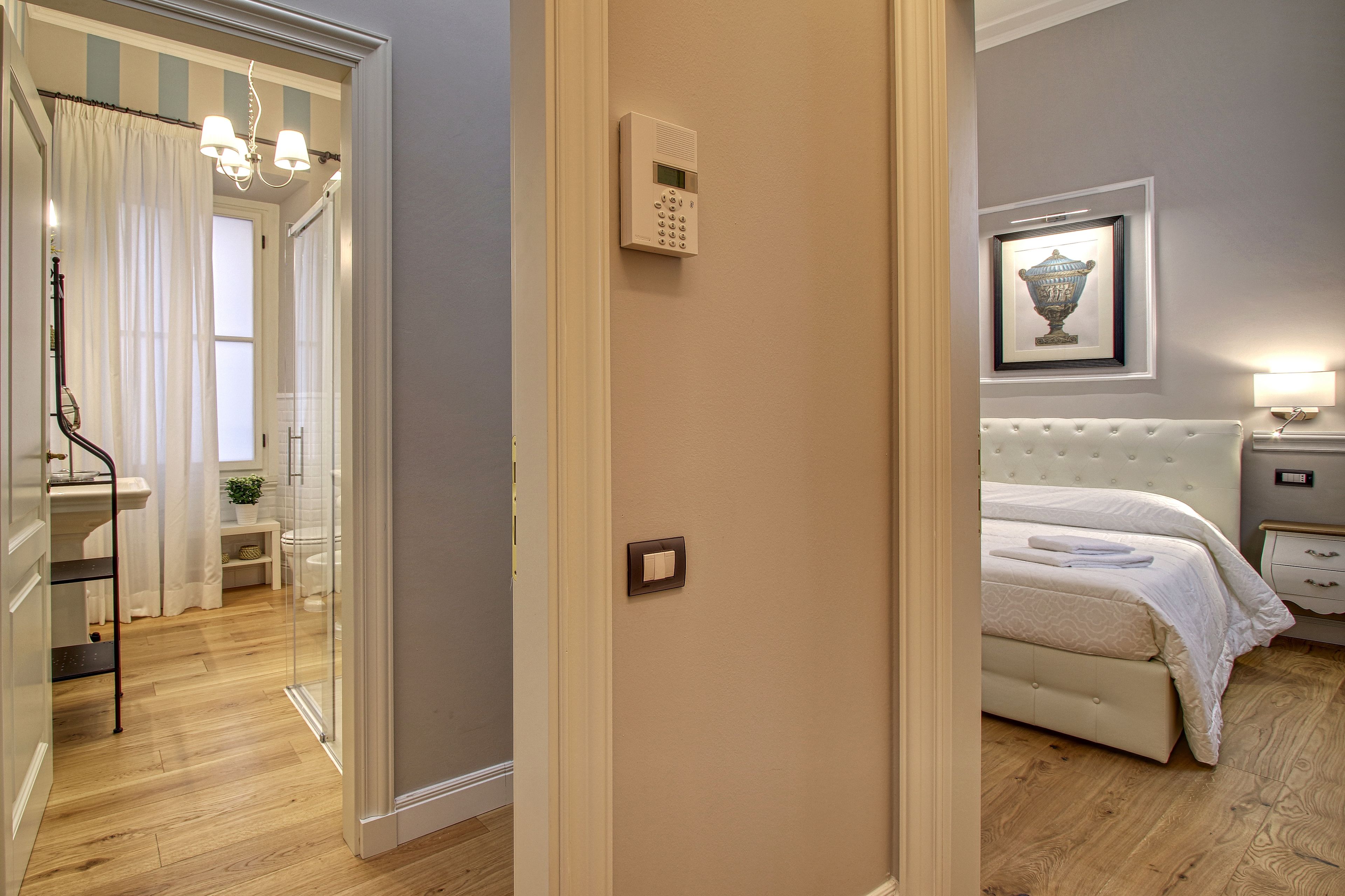 A hotel room with a bed, bedside table, and a framed picture on the wall.