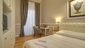 A hotel room with a bed, a desk, a chair, a television, and a framed artwork on the wall. - Art Apartment Campidoglio (Florence)