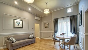 A dining area with a round table and chairs, a sofa, and a framed picture on the wall. - Art Apartment Campidoglio (Florence)