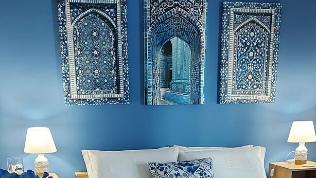 A bedroom with a bed, two nightstands, a blue wall, and three decorative wall pieces. - Casa Del Sole Accomodation (Tropea)