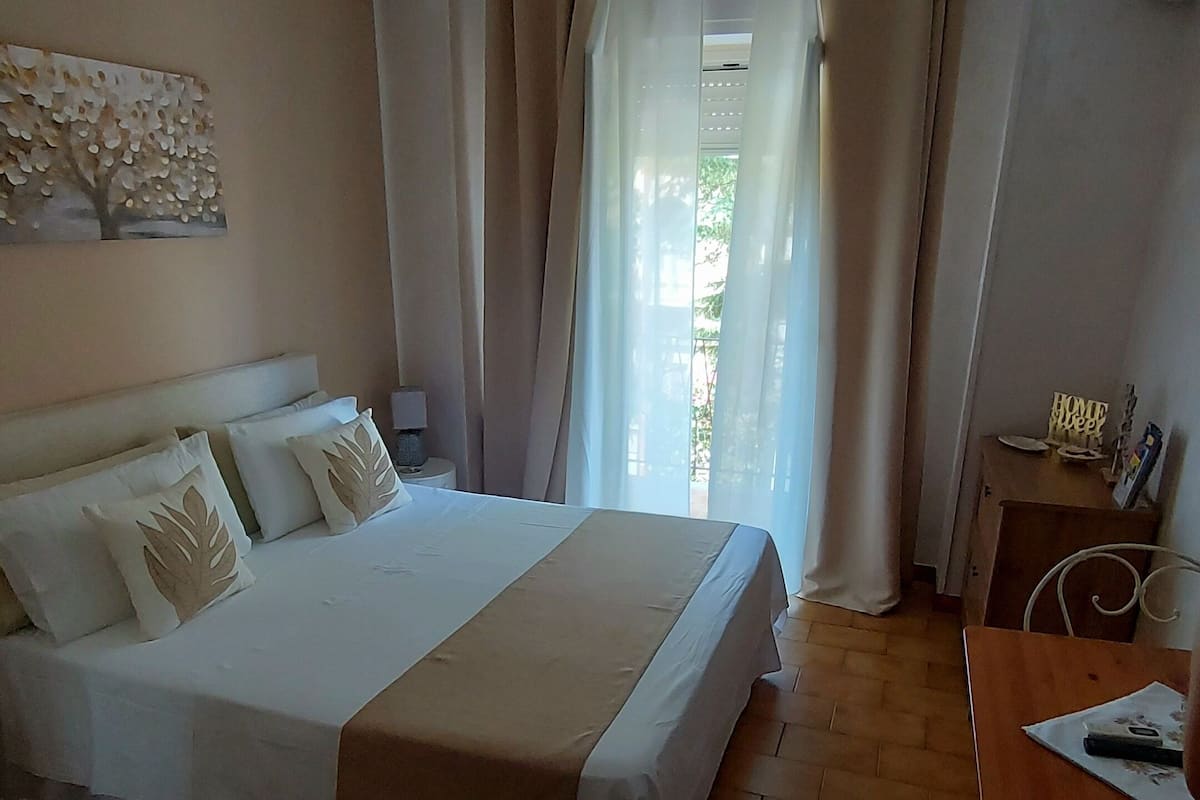 A hotel room with a bed, a desk, and a ceiling fan.