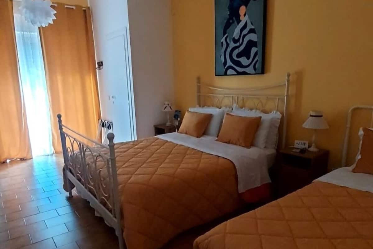 A hotel room with two beds, a painting on the wall, and a chandelier.
