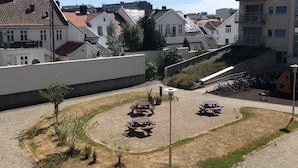 Un patio con mesas de picnic y zona de estacionamiento para bicicletas, rodeado de edificios residenciales.
