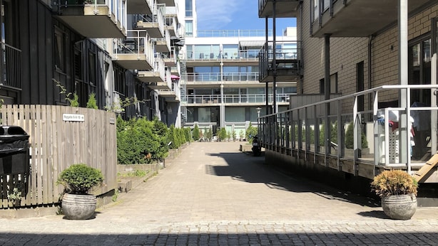 Un edificio residencial de varios pisos con balcones, un patio empedrado y plantas en macetas.