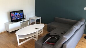 Una sala de estar moderna con un sofá gris, un mueble blanco para televisión y una mesita blanca.
