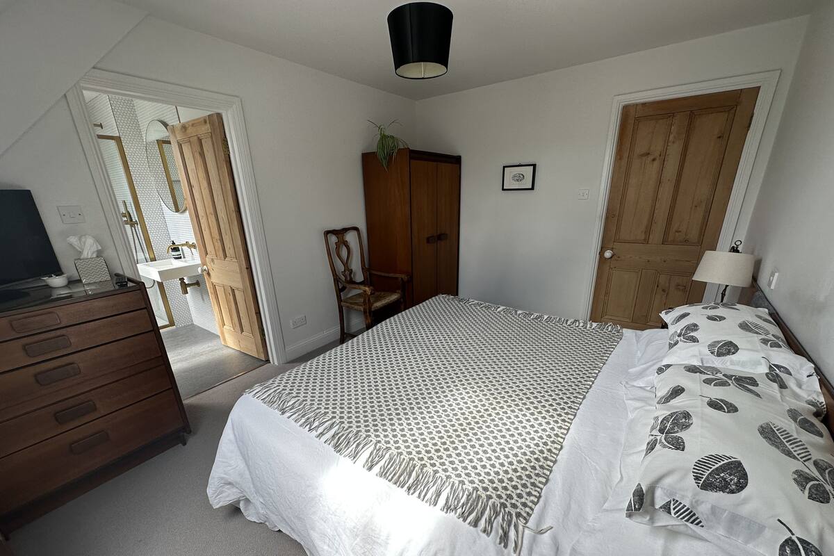 Une chambre à coucher comprenant un lit, une commode, une chaise et une porte donnant sur une autre pièce.