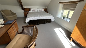 Een slaapkamer met een bed, bureau, stoel en raam.