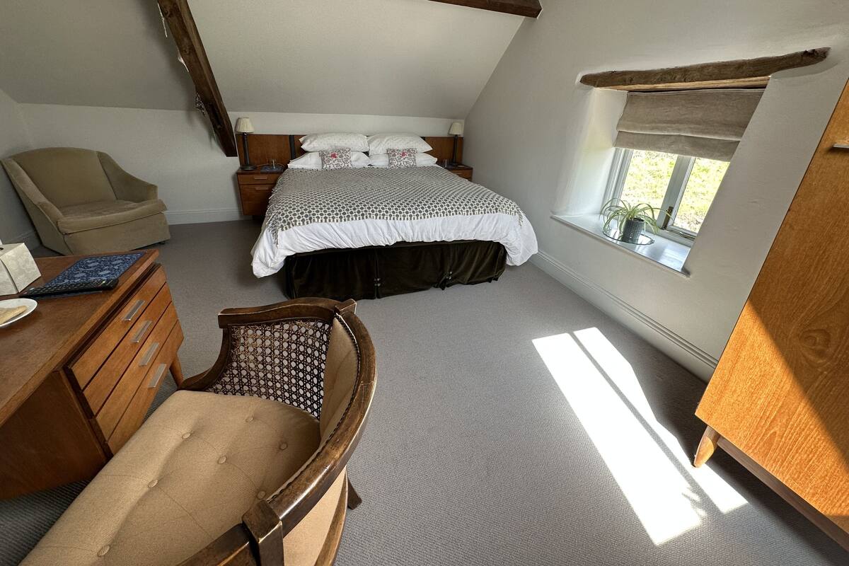 Une chambre à coucher avec un lit, un bureau, une chaise et une fenêtre.