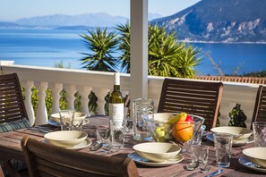 A table set for dining with a bottle of wine, glasses, and a bowl of fruit. - Villa Serenity (Kefalonia)