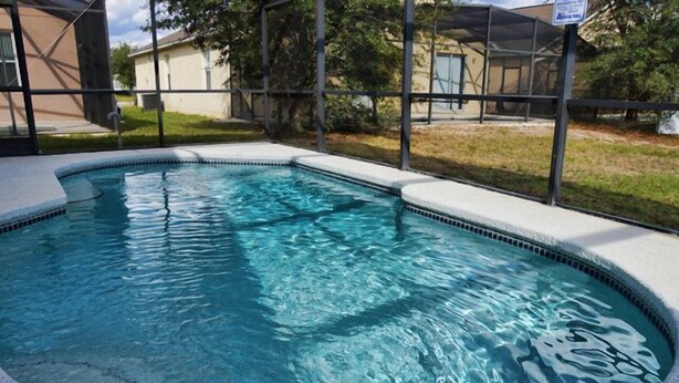 A rectangular swimming pool with a tiled edge, surrounded by a covered area with a metal frame. - Ahr86 - Sunset Ridge - 5 Bed 4 Baths Villa (Davenport)