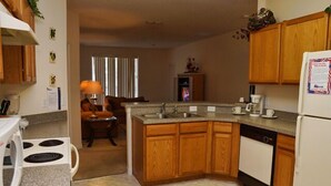 A compact kitchen with wooden cabinets, a built-in dishwasher, and a stove. - Ahr86 - Sunset Ridge - 5 Bed 4 Baths Villa (Davenport)