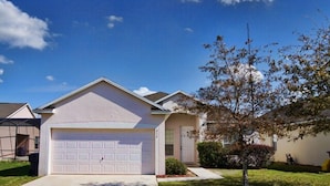 A single-story house with a garage, a small front yard, and a tree. - Ahr86 - Sunset Ridge - 5 Bed 4 Baths Villa (Davenport)