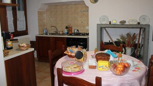 A kitchen with a dining table set for a meal, featuring a basket of bread, a bowl of fruit, and a coffee maker. - La Loggetta (Bagnoregio)