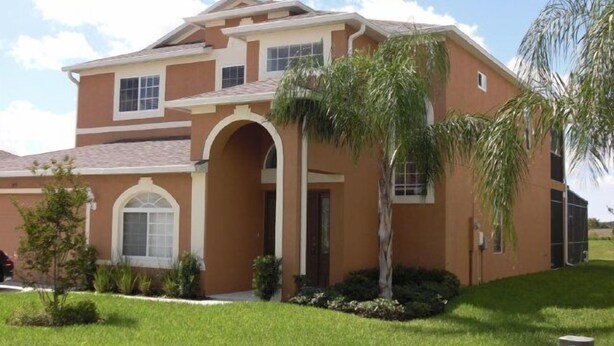 A two-story house with a central arched entrance, a small front yard, and a palm tree. - Ip60471 - The Shire at West Haven - 5 Bed 3 Baths Villa (Davenport)