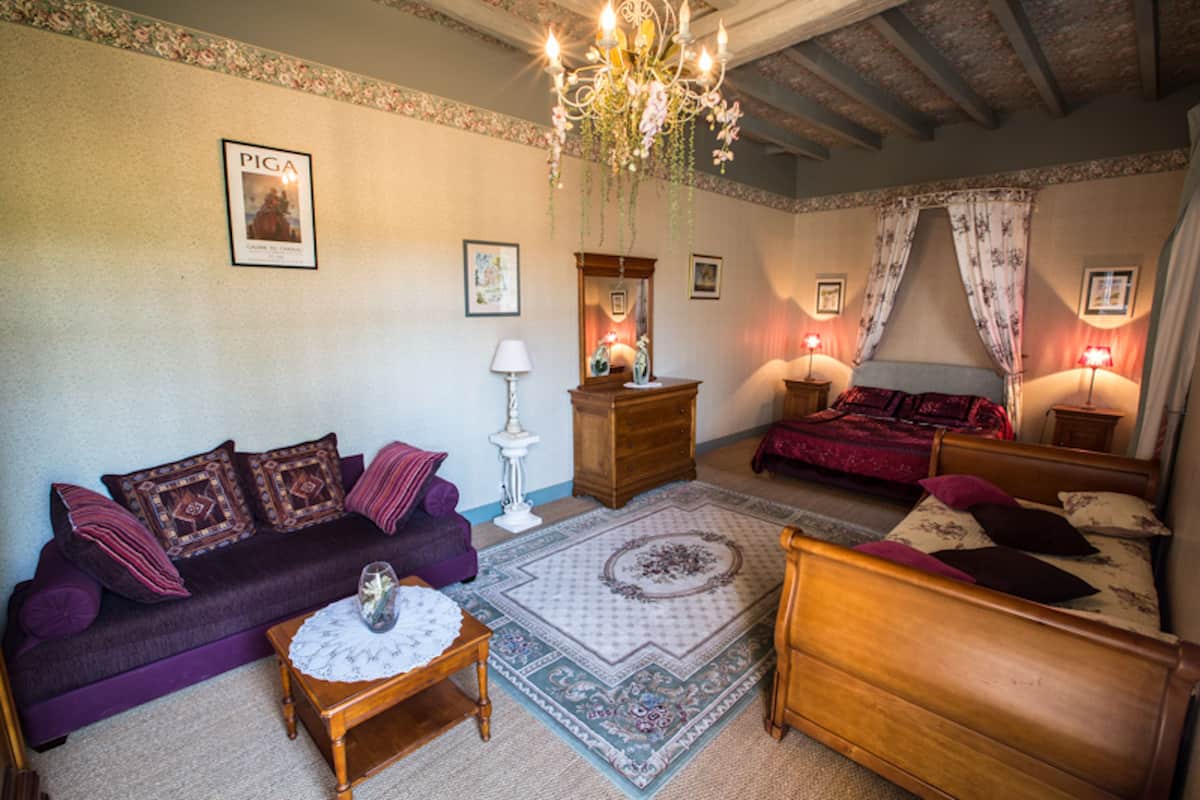 A cozy room with a purple sofa, a wooden bed, and a chandelier.