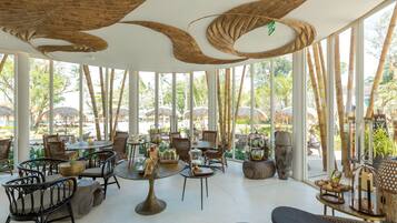 A spacious outdoor seating area with wicker furniture and large windows offering views of the surrounding landscape.