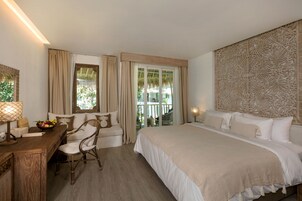 Habitación de hotel con una cama grande, un escritorio con lámpara, una silla y vistas al exterior.