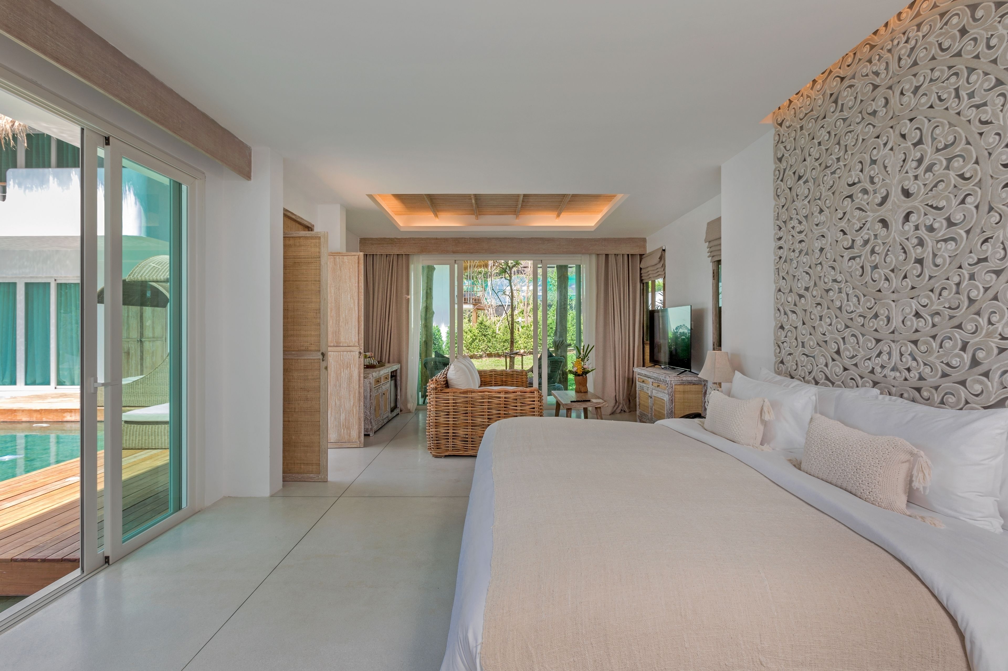 A spacious bedroom with a large bed, a view of a pool, and a balcony.
