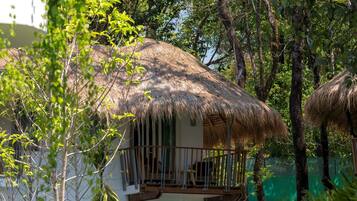 A house with a thatched roof, surrounded by lush greenery and trees.