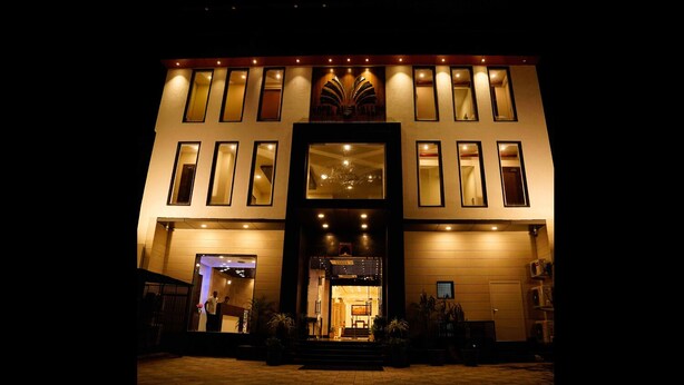 Una entrada de hotel con un amplio portal central, múltiples ventanales y una fachada bien iluminada.