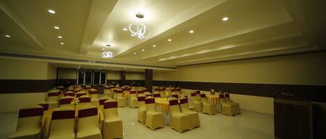 A spacious hall with rows of chairs and tables, recessed lighting, and a decorative ceiling feature.