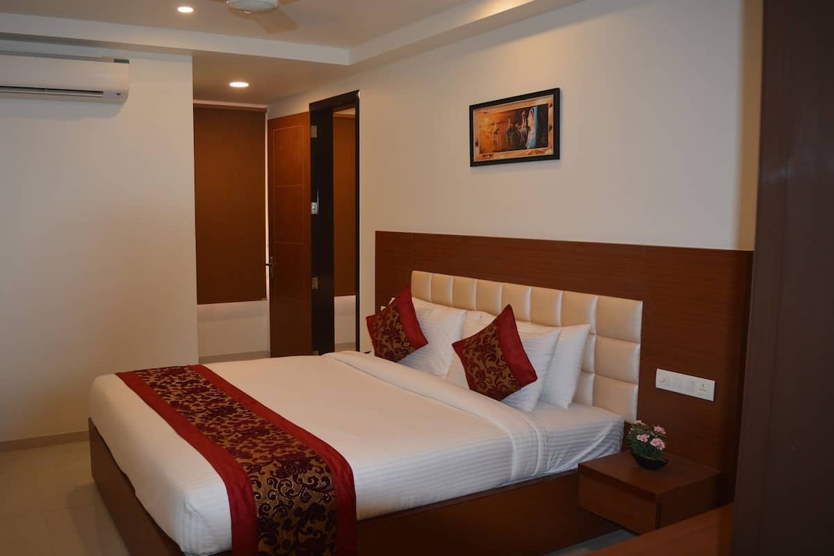 Habitación de hotel con una cama grande, una mesita de noche con lámpara, equipo de aire acondicionado y un cuadro en la pared.