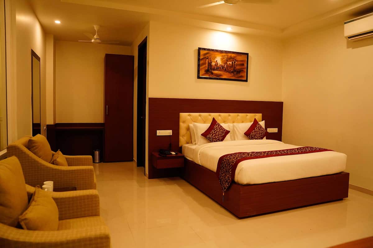 Una habitación de hotel con una cama grande, un sofá, una mesita de noche y un cuadro en la pared.