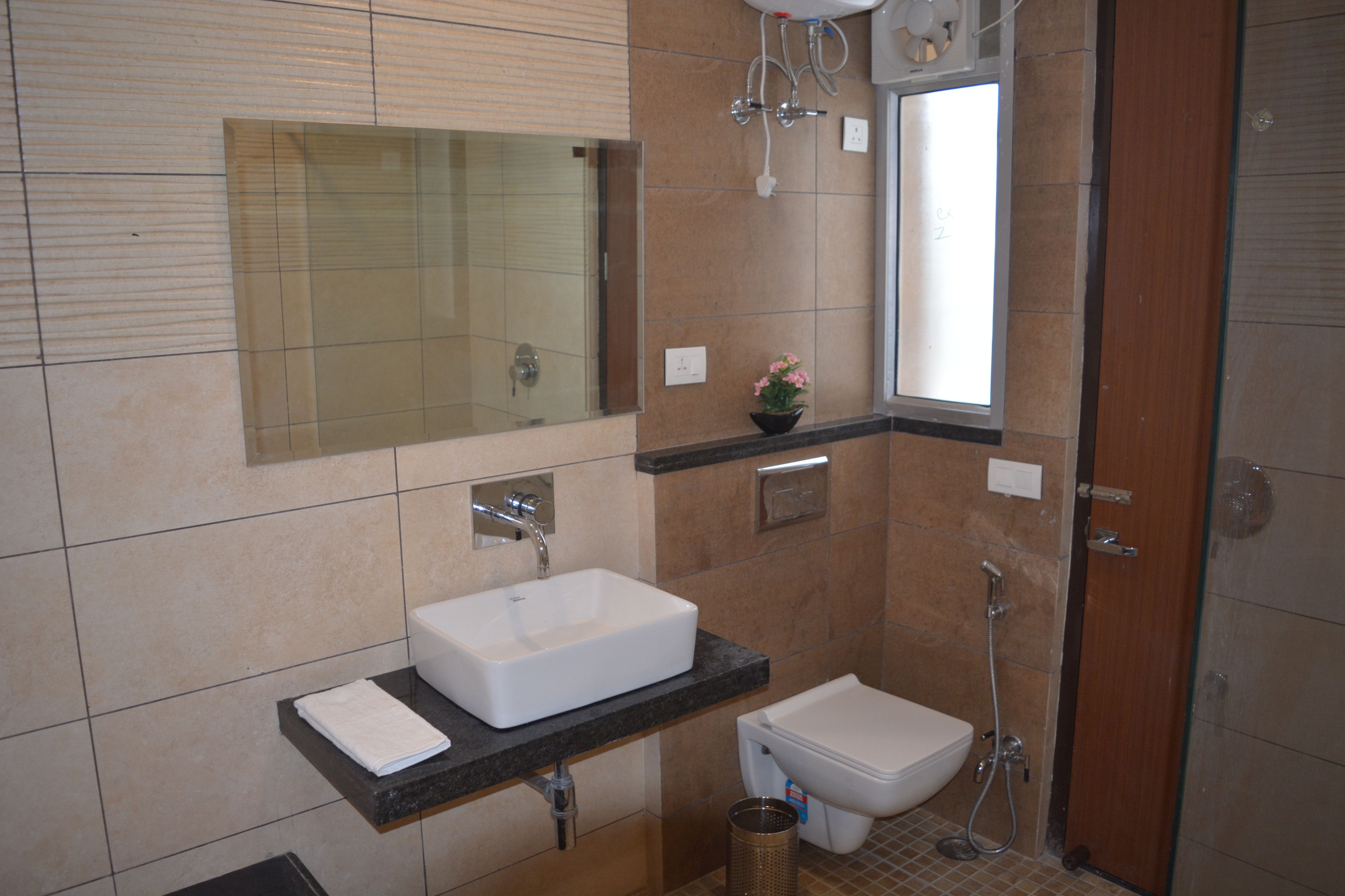 A modern bathroom with a large mirror, a sink, a toilet, and a shower.