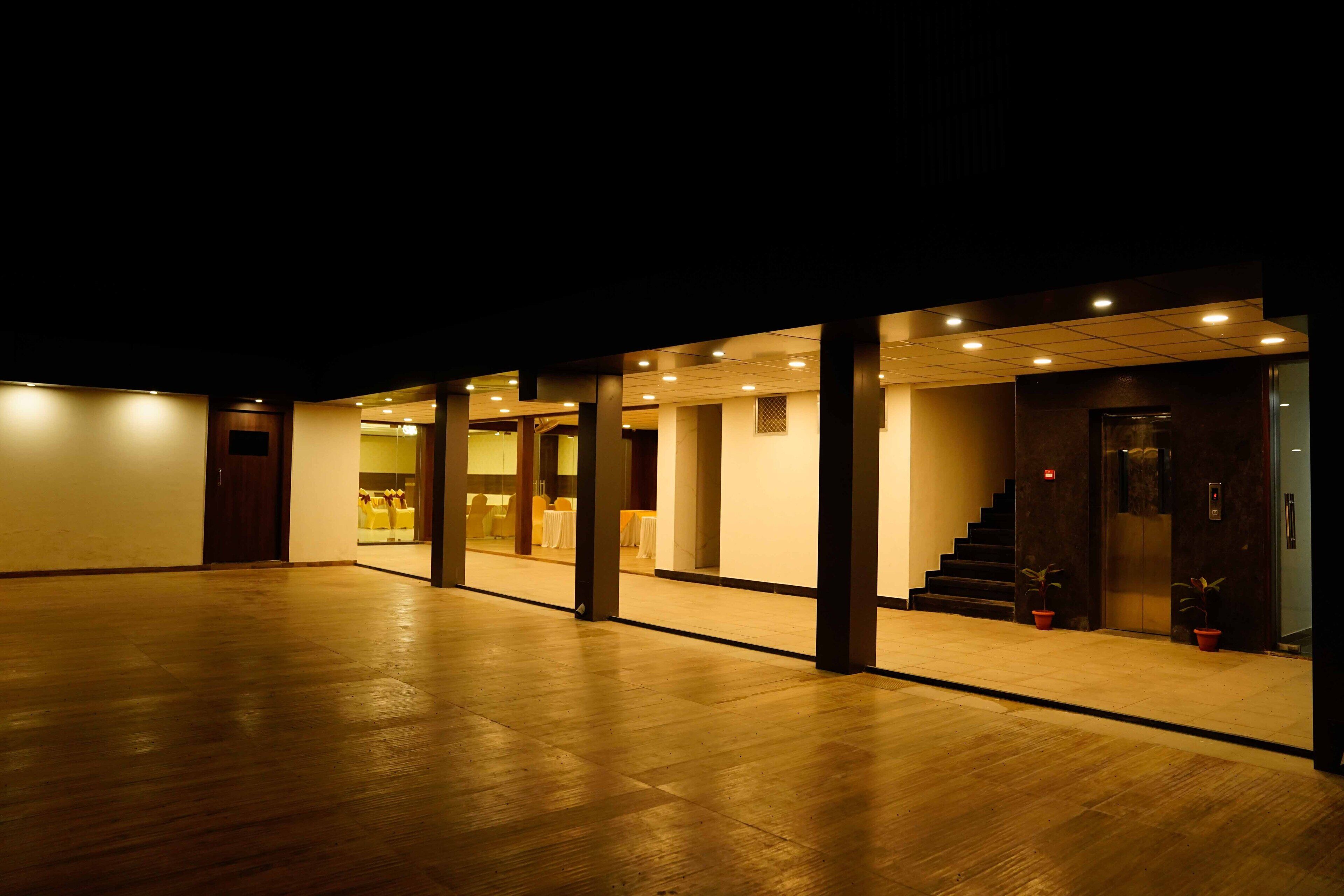 An indoor space with a wooden floor, a staircase, and a door leading to another room.
