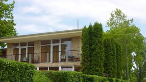 Un bâtiment à deux étages doté d’un balcon, d’un garage et d’une haie bien entretenue.
