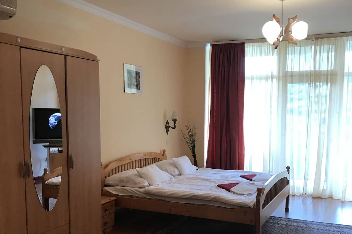 Un dormitorio con cama, armario y televisor sobre un mueble.