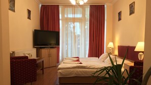 Une chambre d’hôtel équipée d’un lit, d’une télévision, d’un bureau, d’une chaise, d’une lampe et d’une plante.