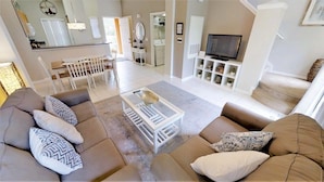 A spacious living area with a sofa set, a coffee table, and a television. - Aco238226 - Emerald Island Resort - 3 Bed 2.5 Baths Townhome (Kissimmee)