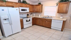 A kitchen with wooden cabinets, a white refrigerator, a microwave, a stove, a sink, and a dishwasher. - Bjw538 - Sandy Ridge - 4 Bed 3 Baths Villa (Davenport)