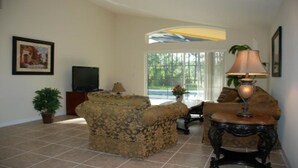 A living room with a sofa, a table, a lamp, a television, and a potted plant.
