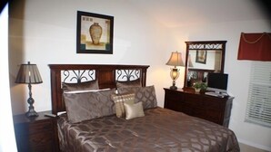 A neatly made bed with a patterned bedspread, a wooden headboard, and two bedside lamps.