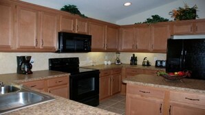 A kitchen with wooden cabinets, a microwave, a stove, and a refrigerator.