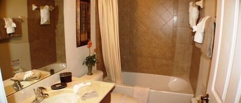 A bathroom with a sink, mirror, toilet, and bathtub.